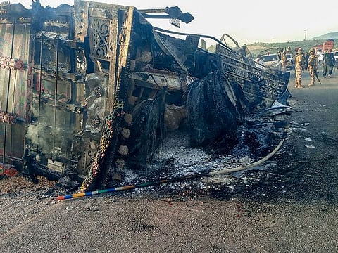 Security personnel stand guard near the charred vehicle at the shooting site on the national highway in Musakhail district, Balochistan province on August 26, 2024.  
