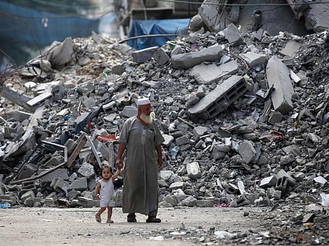 An elderly man and a child walk past a building levelled by Israeli bombardment in the Bureij refugee camp in central Gaza Strip on August 25, 2024.