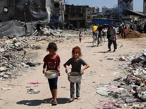 Palestinian children carry pots of soup near a food distribution point in the Jabalia refugee camp in northern Gaza Strip on August 21, 2024, amid the ongoing conflict in the Palestinian territory between Israel and Hamas.