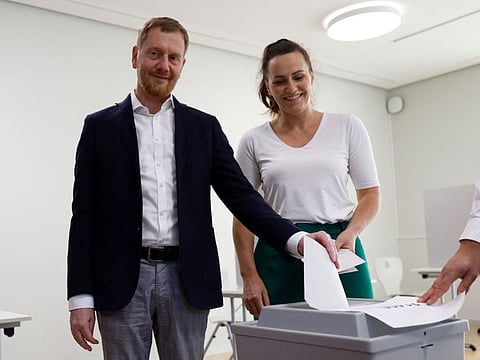 Saxony's State Premier and top candidate of the conservative Christian Democratic Union (CDU) party for regional elections in Saxony Michael Kretschmer casts his ballot for Saxony's regional elections as his wife Annett Hofmann looks on at a polling station in Dresden, eastern Germany, on September 1, 2024. 