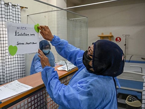 A health worker installs a poster indicating an isolation ward prepared for mpox patients at the Police and Services hospital in Peshawar on August 20, 2024.  