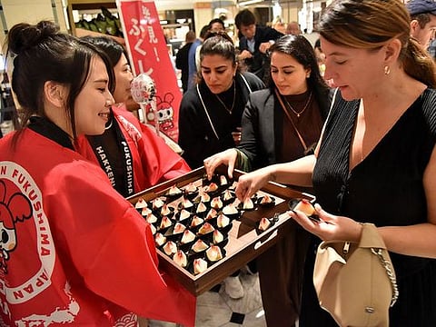 A customer (R) trying peaches from Japan's Fukushima prefecture, which went on sale at luxury department store Harrods in central London.