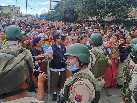 Protesters gather as security personnel block their way along a street during a curfew in Imphal on September 10, 2024.