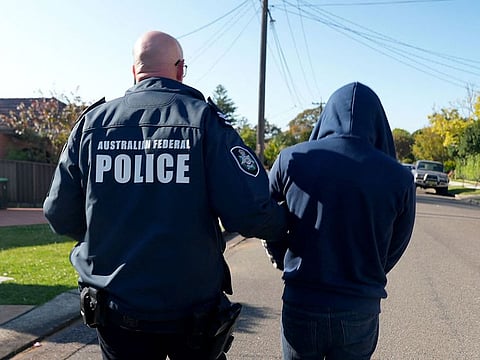 An Australian Federal Police officer arresting a suspect allegedly involved in an encrypted messaging app used by criminals worldwide to facilitate drug deals and order killings, at an unknown location.  