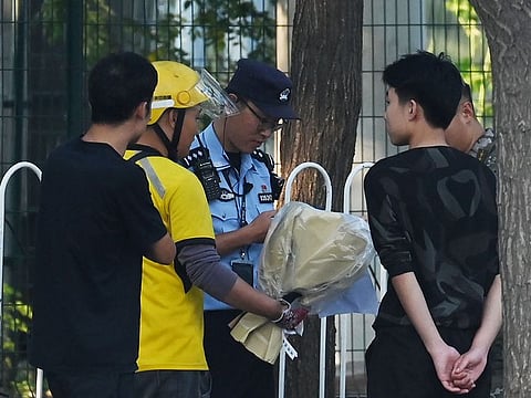 Police and security check a delivery rider (2nd L) who arrived with what appeared to be a bouquet of flowers at the entrance of the Japanese embassy in Beijing on September 19, 2024. 