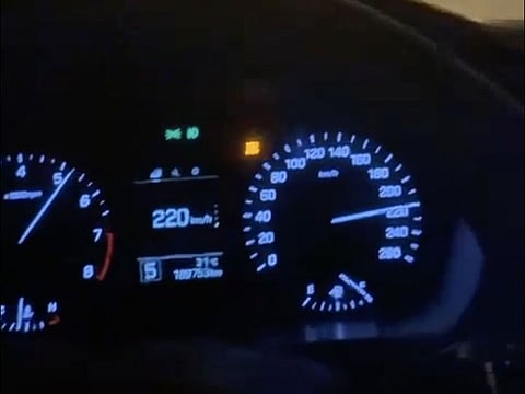 Screenshot of a video showing a car's speedometre reading of 220km/h on a Dubai highway