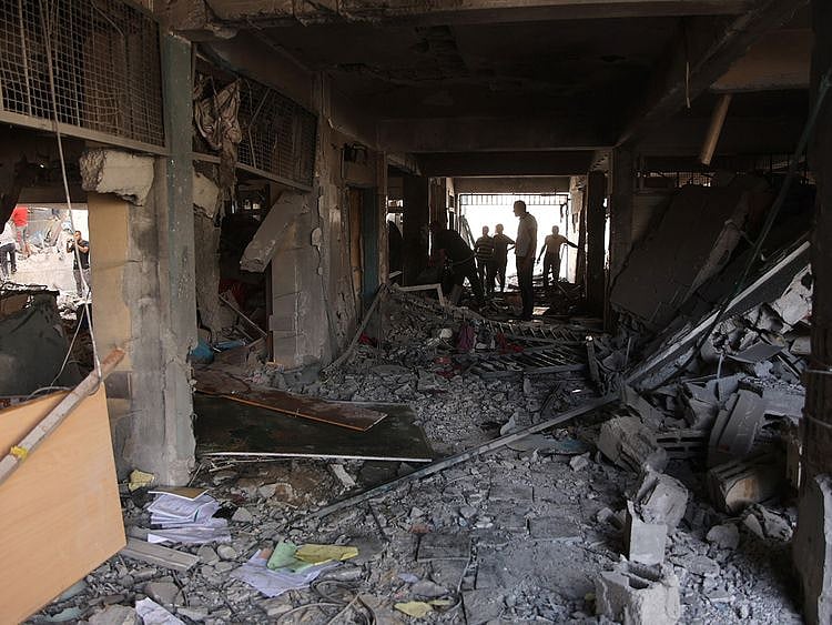Palestinians inspect the damage at the site of an Israeli strike