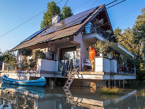 A man stands on a flooded house as a canoe floats on the water in Hungary, on September 20. High winds and unusually heavy rainfall have hit swathes of Austria, the Czech Republic, Hungary, Poland, Romania and Slovakia since last week. 