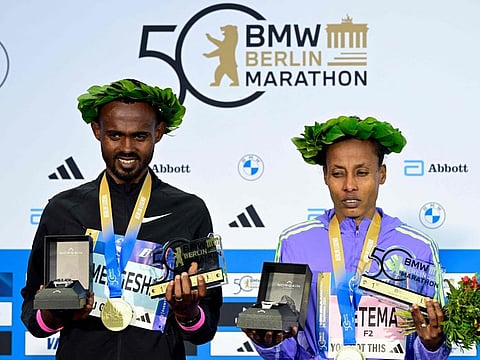 Winners Ethiopia's Milkesa Mengesha (left) and Ethiopia's Tigist Ketema celebrate on the podium after the 50th edition of the Berlin Marathon in Berlin, Germany on Sunday.