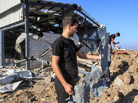 People inspect a destroyed warehouse at the site of an Israeli air strike in Jiyeh along the highway linking Beirut to the southern city of Sidon on September 25, 2024