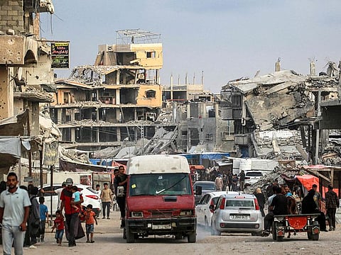 Vehicles move past destroyed buildings in Khan Yunis in the southern Gaza Strip on October 6, 2024 on the eve of the anniversary of the ongoing war in the Palestinian territory between Israel and Hamas. 