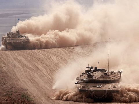 Israeli army tanks drive in an area near Israel's southern border with the Gaza Strip