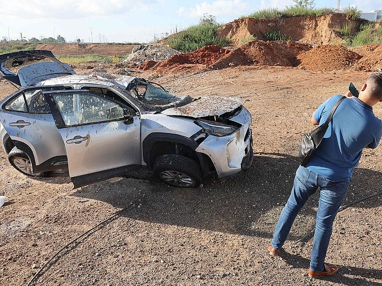  A man takes a picture of a damaged vehicle in the aftermath of an Iranian missile attack on Israel, on October 2, 2024 in Tel Aviv.  