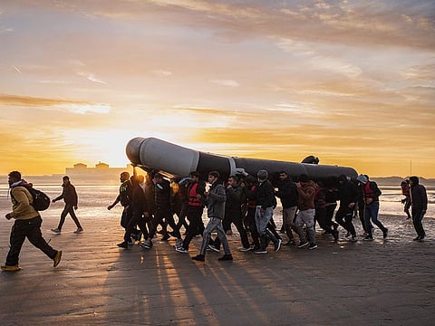 File photo: Migrants carry a smuggling boat on their shoulders as they prepare to embark on the beach of Gravelines, near Dunkirk, northern France, in a attempt to cross the English Channel. 
