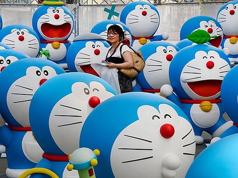 A journalist walking amid life-size figures of Doraemon during the press preview of the Fujiko F Fujio Exhibition in Tokyo.
