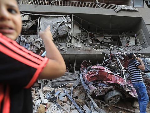 People walk past a damaged building at the site of an Israeli strike on the Basta neighbourhood in the Lebanese capital Beirut on October 11, 2024. 