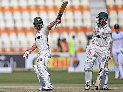 Pakistan's Kamran Ghulam celebrates with teammate Saim Ayub after scoring a half-century during the first day of the second Test cricket match against England at the Multan Cricket Stadium in Multan on Tuesday.