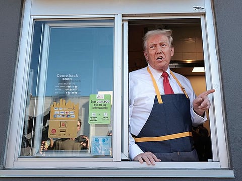 Former US President Donald Trump answers questions as he works the drive-through line as he visits a McDonald's restaurant.