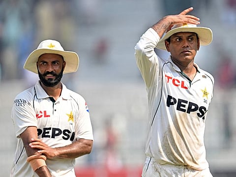 Pakistan's Noman Ali (right) and Sajid Khan walk back after winning the second Test cricket match against England at the Multan Cricket Stadium in Multan on October 18.