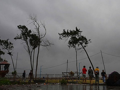 Dark clouds loom over the Bay of Bengal as local people and tourists stand along a beach in Digha, around 200km southwest of Kolkata, on October 24, 2024, as cyclone Dana is likely to hit the coasts of India's West Bengal and Odisha states. 