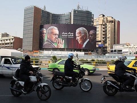 Commuters drive past a billboard bearing pictures of Iran's President Masoud Pezeshkian (2-L), armed forces chief of staff Major General Mohammad Bagheri (L) US President Joe Biden (2-R) and Israeli Prime Minister Benjamin Netanyahu (R) in Vali-Asr square in Tehran on October 27, 2024.   