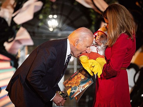 US President Joe Biden jokingly bites a baby dressed as a chicken as he hosts a Halloween trick-or-treat event at the South Portico of the White House in Washington, DC, on October 30, 2024