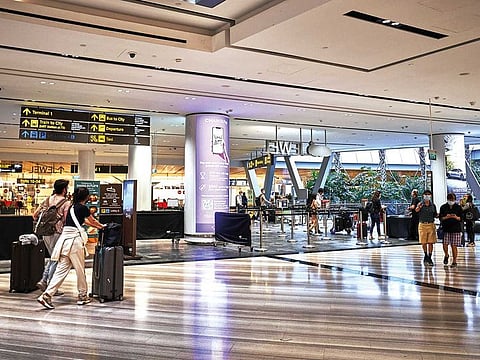 Travelers with baggage near Terminal 1 at Jewel Changi Airport mall near in Singapore.