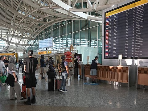 Passengers look at an electronic board displaying cancelled flights at the Ngurah Rai International Airport in Tuban near Denpasar, on Indonesia's resort island of Bali.