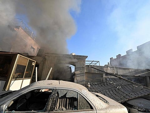 Damaged cars lie in front of a smouldering building hit by a reported Israeli strike in the Mazzeh district of Damascus on November 14, 2024.  