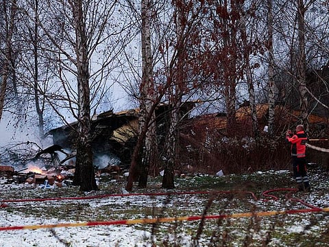 A Lithuanian medic takes a photo on his mobile phone of the wreckage of a cargo plane following its crash near the Vilnius International Airport in Vilnius on November 25, 2024. A DHL cargo plane flying from Germany to Lithuania crashed early on November 25, 2024 near the airport of the capital Vilnius killing one person, firefighters said. 
