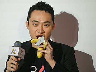 Chinese-born crypto founder Justin Sun eats a banana artwork composed of a fresh banana stuck to a wall with duct tape, in Hong Kong on November 29, 2024, after buying the provocative work of conceptual art by Italian artist Maurizio Cattelan at a New York auction for $6.2 million. 