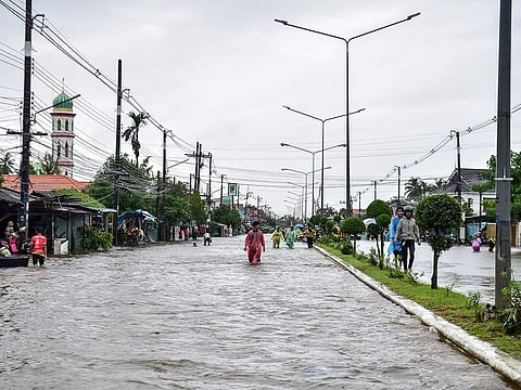 People through flood waters along a street following heavy rain in Thailand's southern province of Narathiwat on November 28, 2024. 