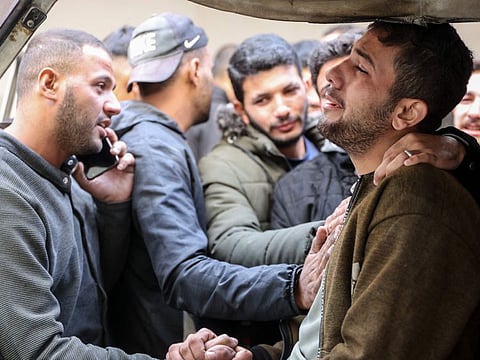 A Palestinian man is comforted by others as bodies of victims of an Israeli strike in Gaza City's Daraj neighbourhood are brought to a hospital (not pictured), on December 5, 2024, amid the ongoing war between Israel and Hamas militants. (Photo by Omar AL-QATTAA / AFP)
