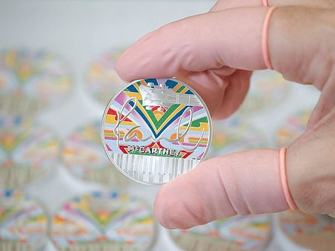 An undated handout picture released by The Royal Mint, received in London on December 5, 2024, shows the design of the Paul McCartney £5 coin being held by a Royal Mint worker. 