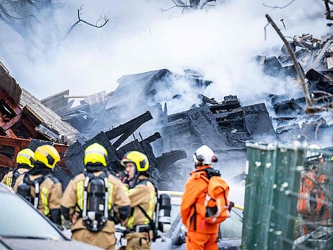 Firemen stand next to a partially collapsed residential building following a fire and an explosion in The Hague on December 7, 2024. 