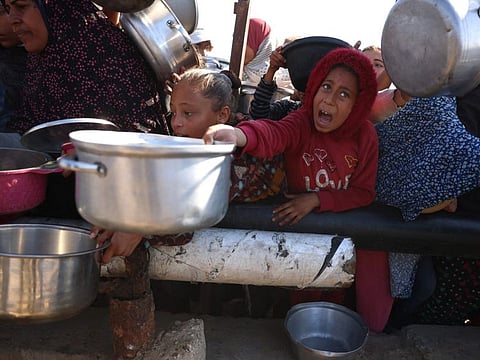 Palestinians stand in wait for a food portion at a distribution centre south of Khan Yunis in the southern Gaza Strip on December 17, 2024.