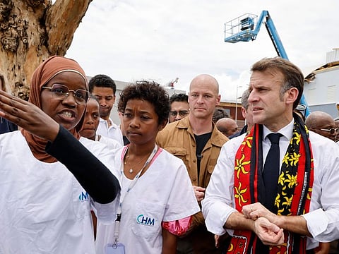 France's President Emmanuel Macron (right) reacts next to a medical staff member at the Mayotte Hospital Centre in Mamoudzou, on the French Indian Ocean territory of Mayotte, on December 19, 2024.