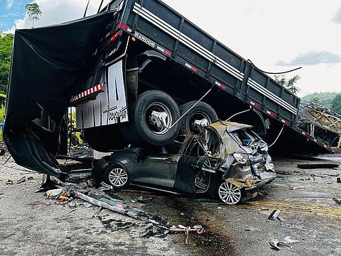 Handout picture released by Minas Gerais Fire Department shows a truck on top of a car on the site of a crash in Teofilo Otoni, Minas Gerais state, Brazil on December 21, 2024. 