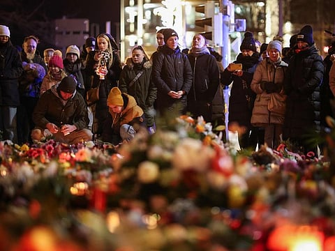 People stand at a makeshift memorial near the site of a car-ramming attack on a Christmas market in Magdeburg, eastern Germany, on December 21, 2024.  