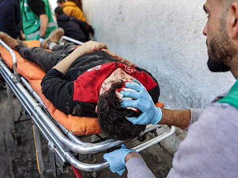 Palestinian Red Crescent paramedics transport on a gurney a person who was injured in a reported strike on a Palestinian civilian vehicle by Israeli forces, after arriving for medical care at the Ahli Arab Hospital in Gaza City on December 22, 2024.