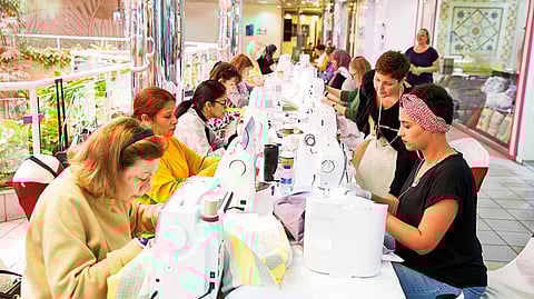 Participants in the forthcoming show sew their quilts on individual machines 
