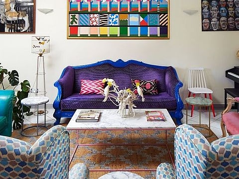 The living room is a riot of colour with mismatched pre-loved sofas given a new life with a splash of paint. 