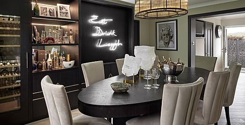 The neon sign is a fun focal point in the dining area, surrounded by sleek, sophisticated furnishings for a memorable entertaining interior 