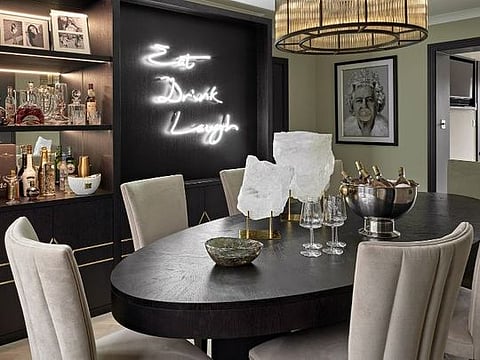 The neon sign is a fun focal point in the dining area, surrounded by sleek, sophisticated furnishings for a memorable entertaining interior 