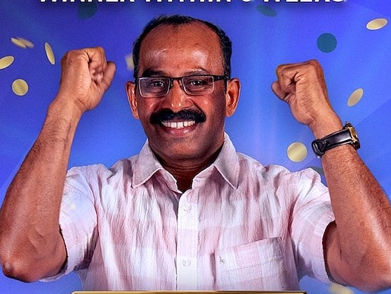 Sunil Kumar Sadasivan holds a giant ceremonial check for thirty million dirhams while smiling at a press event.