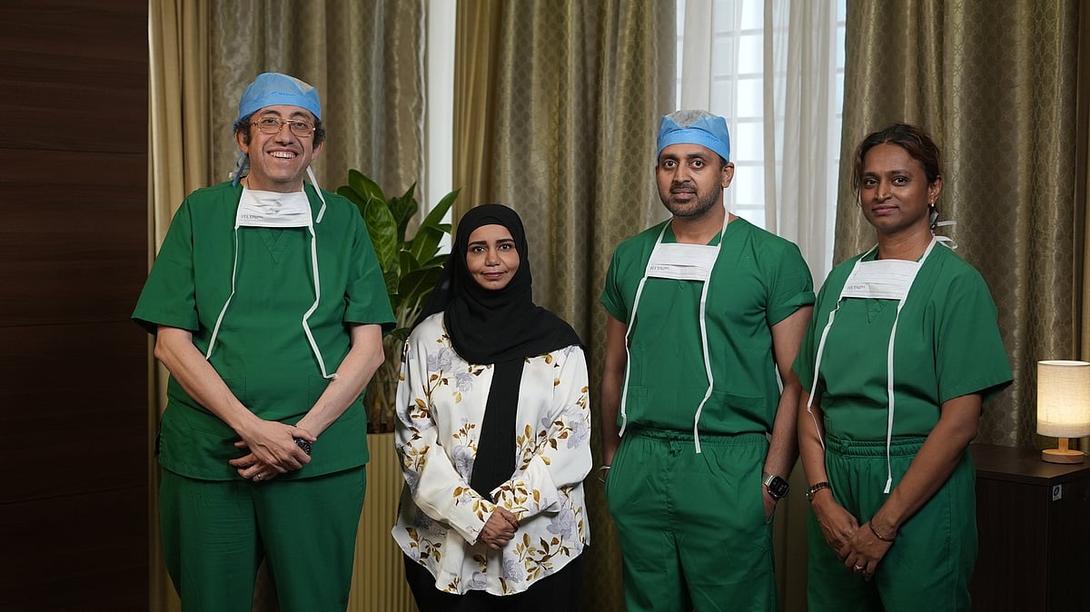 Medical professionals in scrubs perform a specialized surgical procedure under bright theater lights in an operating room.