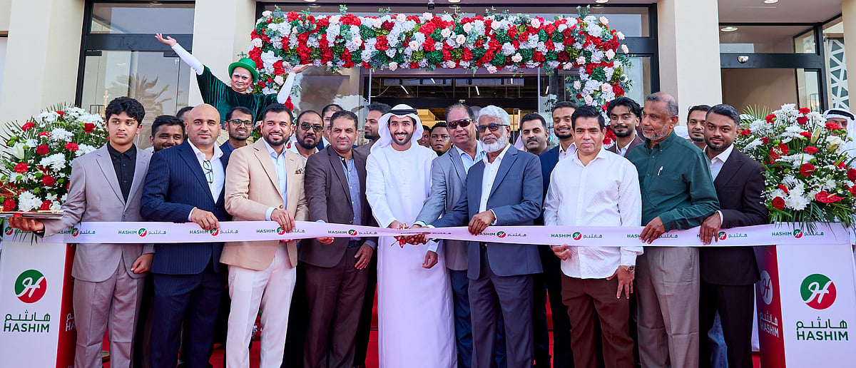 Dignitaries and executives cut a ceremonial ribbon at the brightly lit entrance of a new Al Yarmook hypermarket.