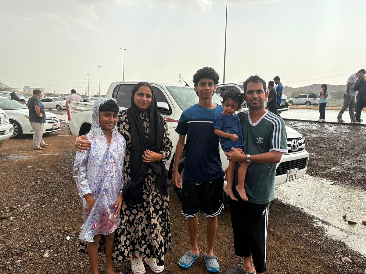 Heavy rain and hail fall over the rugged Al Hajar Mountains as dark storm clouds gather during a summer storm.