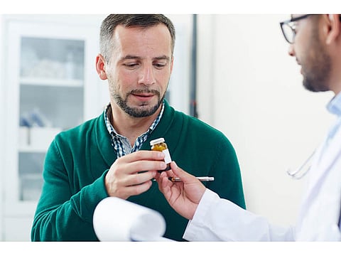 doctor with a patient handing him a bottle with pills