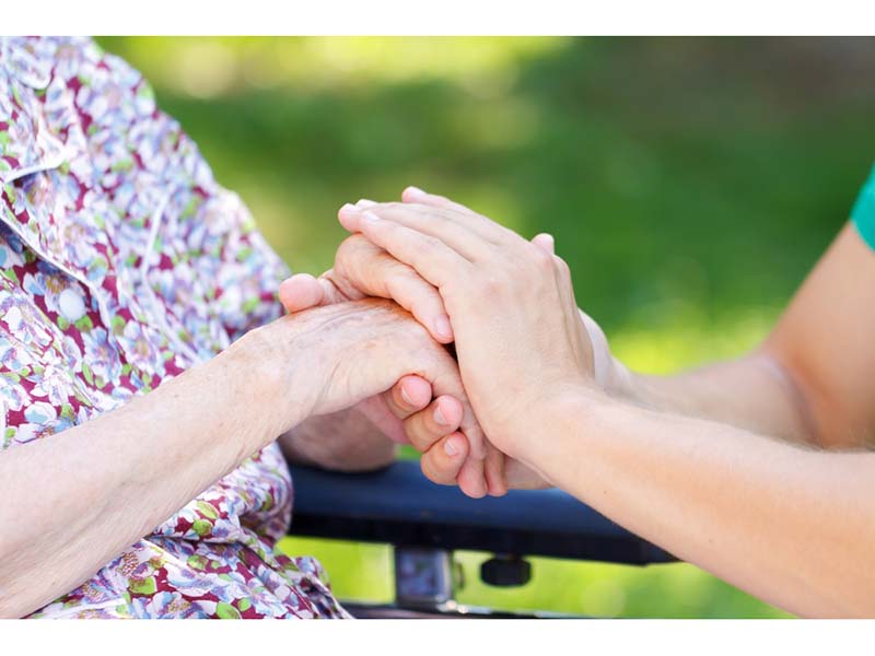 caregiver holding elderly person\'s hand